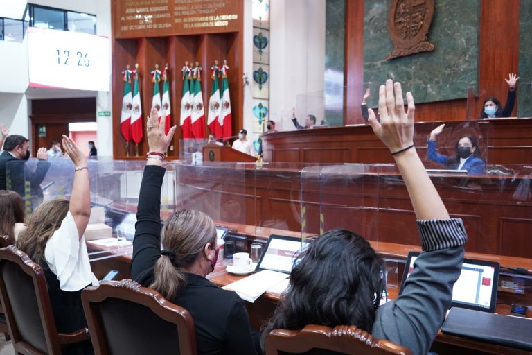 Todas las diputadas y diputados votan a favor del presupuesto estatal con el brazo en alto.