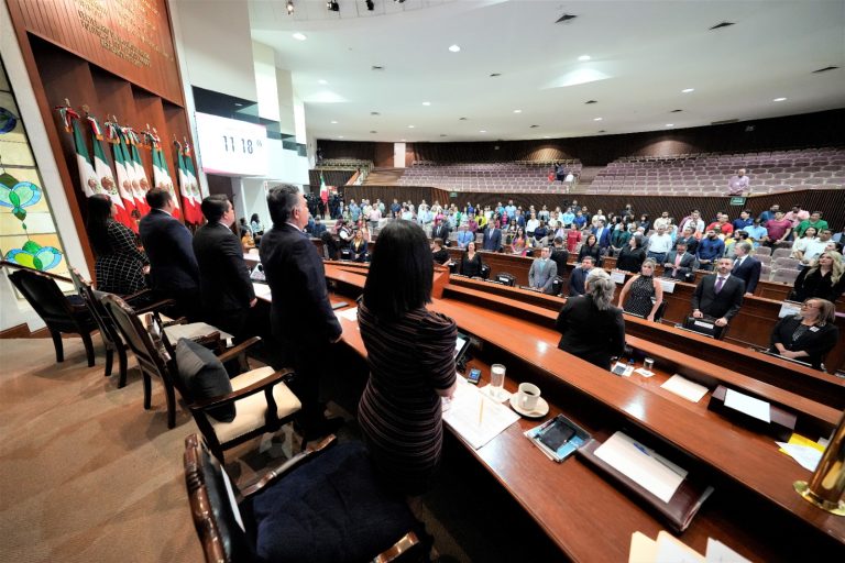 Diputadas y diputados aparecen de pie en Sesion Solemne. Al fondo, público asistente.
