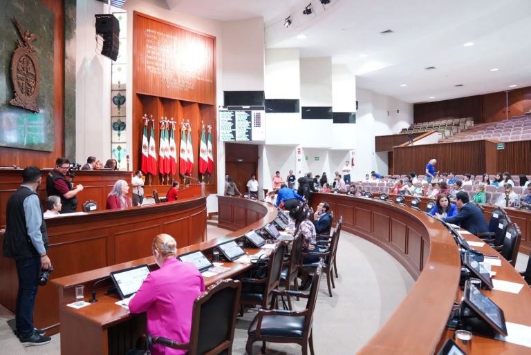 Visa lateral del Salón de Sesiones. Diputadas y diputados se observan sentados en hileras.