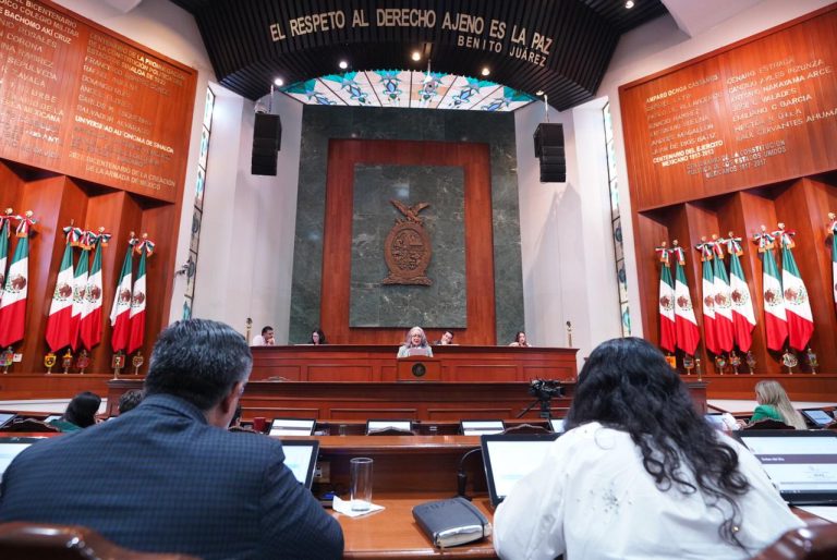Toma frontal de la Mesa Directiva. En primer plano una diputada y un diputado, y al fondo quienes forman parte de esa mesa.