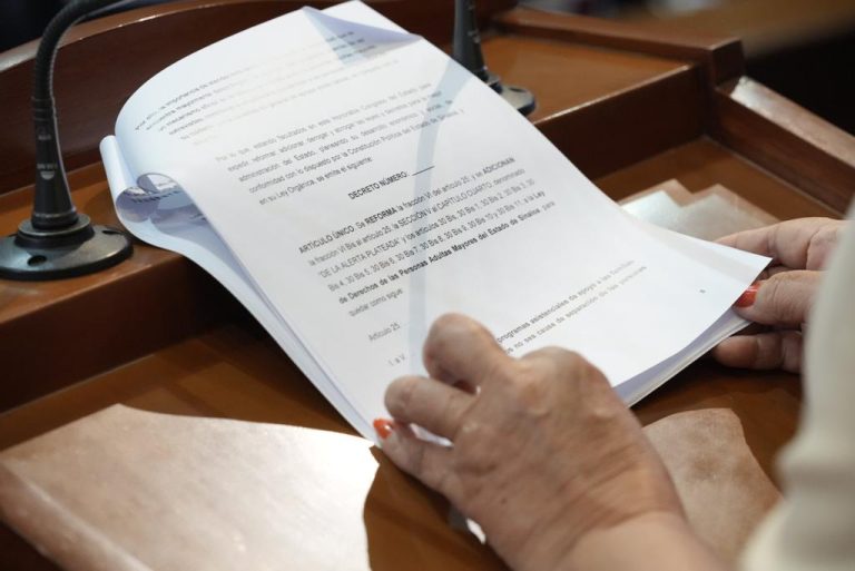 Documento que es leído en tribuna es sostenido por par de manos.
