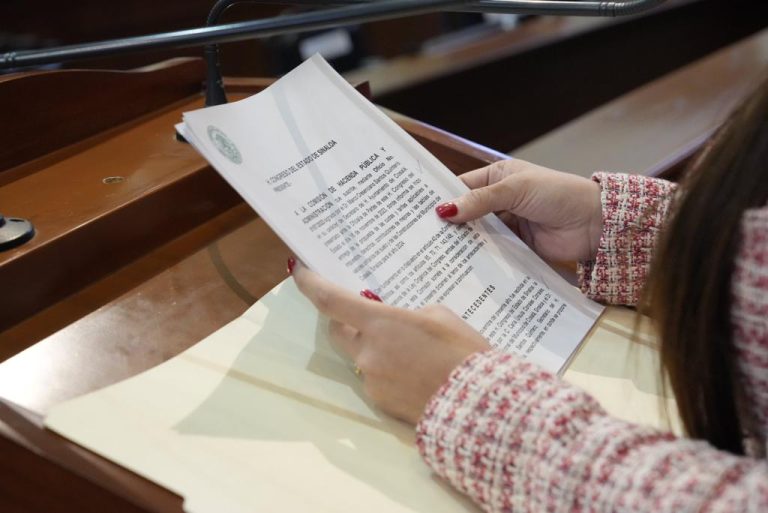 Par de manos sostienen documento al que se le da lectura en tribuna.