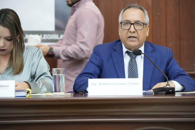 Diputado Ambrocio Chávez, de traje azul, habla sentado en presidium ante micrófono.