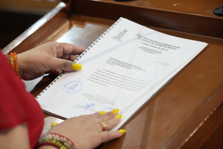 Par de manos sostiene documento al que se le da lectura en tribuna.