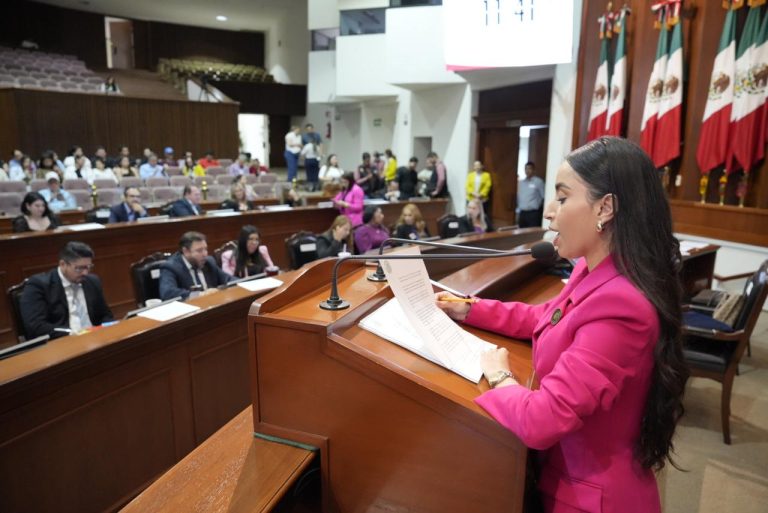 Diputada secretaria da lectura de pie en tribuna a documento.