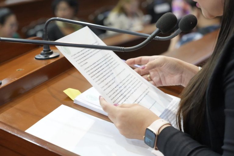 Par de manos sostiene documento al que se le da lectura en tribuna,