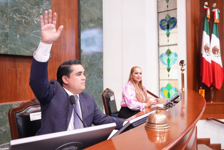 Presidente de Mesa Directiva vota levantando su mano desde su silla. Le mira diputada vicepresidenta.