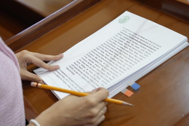 Par de manos sostiene documento al que se le da lectura en tribuna.