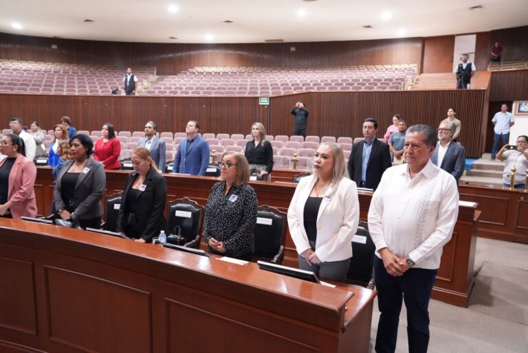 Diputadas y diputados guardan un minuto de silencio y permanecen parados.