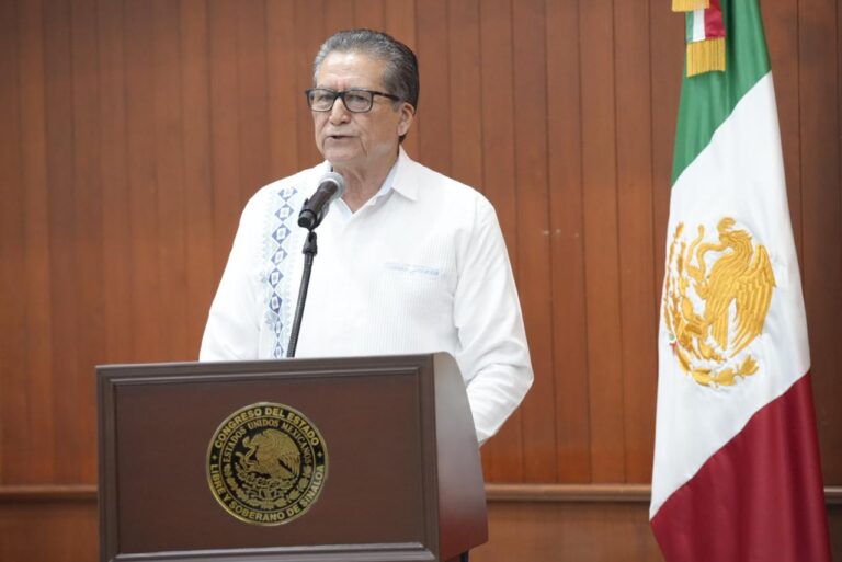 Diputado Feliciano Castro habla en podio, junto a una bandera de México.
