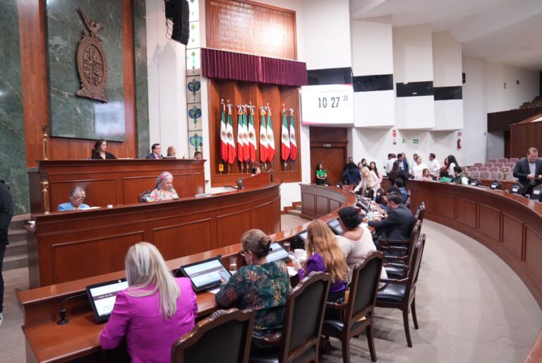 Vista lateral de la Sala de Sesiones en la que se observa una fila de diputadas y diputados frente a Mesa Directiva.