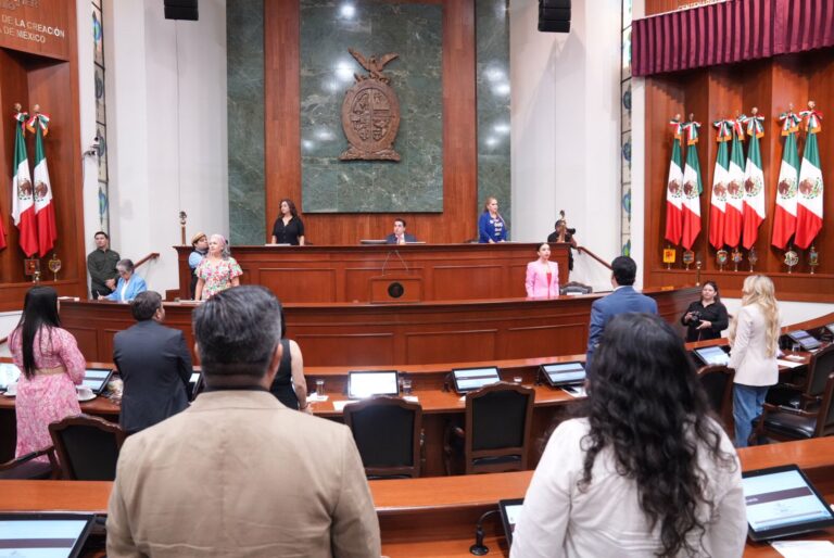 Diputados y diputadas aparecen de espaldas frente a Mesa Directiva. Al fondo y en lo alto enorme escudo del Estado de Sinaloa.