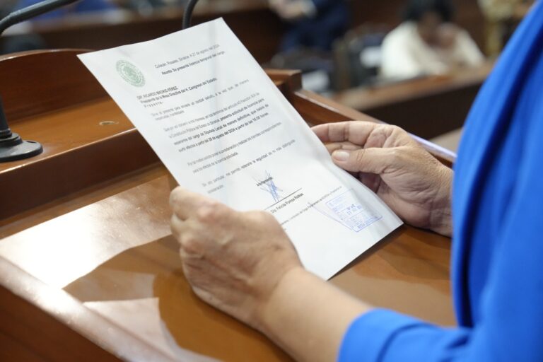 Par de manos de diputada sostiene documento al que le da lectura en tribuna.