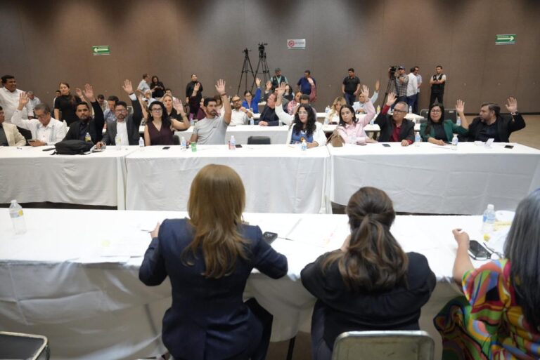 Diputadas y diputados votan levantando su mano De espaldas aparecen integrantes de Mesa Directiva.