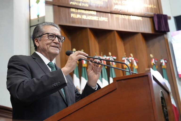 Diputado Feliciano Castro acomoda micrófonos en tribuna al dar su mensaje.