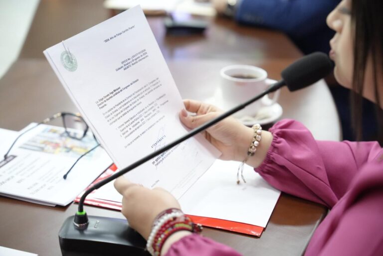 Diputada da lectura ante micrófono que sostiene con ambas manos.