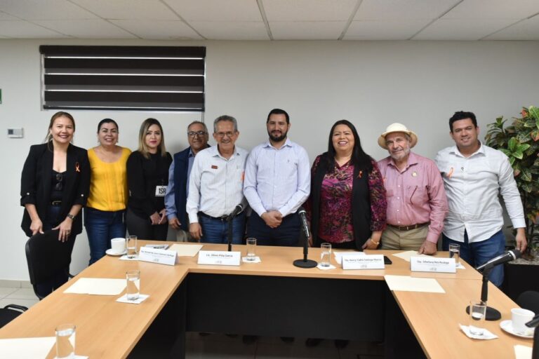 Integrantes de Comisión posan de pie para la foto junto con invitado.