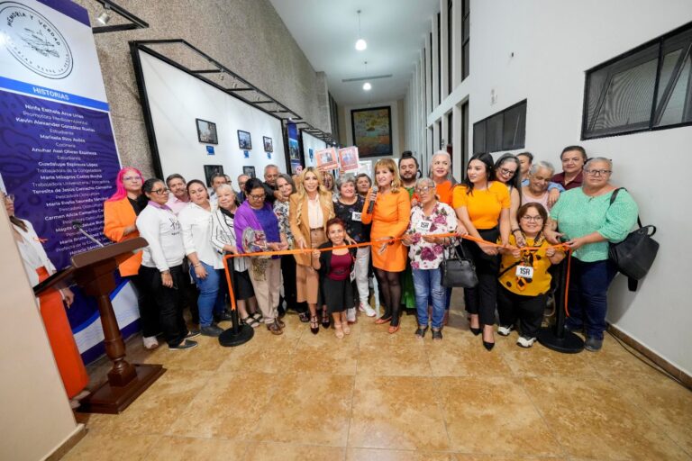 Diputadas, expositoras y público cortan el listón simbólico para inaugurar exposición.