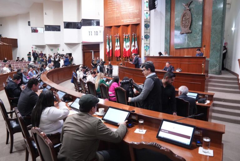 Vista lateral del Salón de Sesiones, con diputados sentados en sus asientes y al fondo la Mesa Directiva.