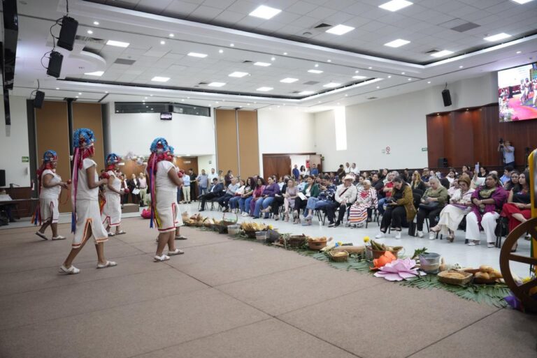 Danzantes indígenas sobre templete colocado y frente a un amplio público.