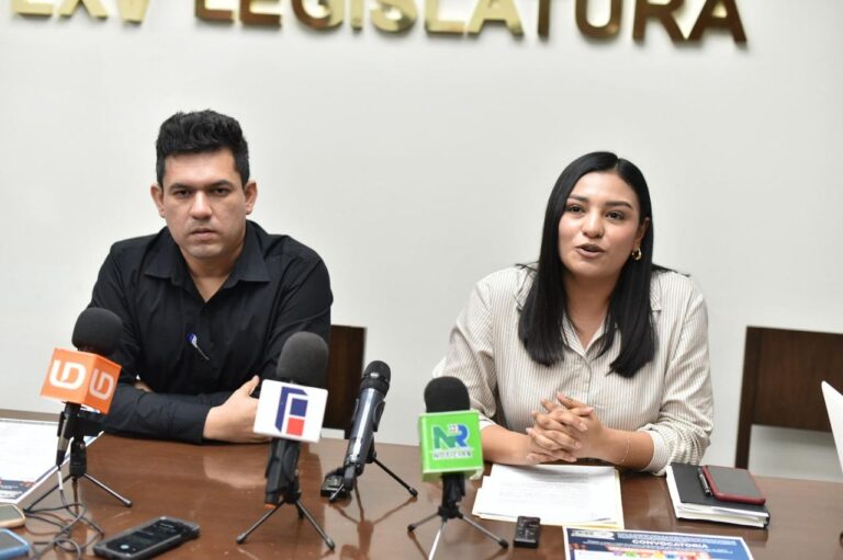 Diputada y diputada sentados frente a micrófonos durante conferencia de prensa.
