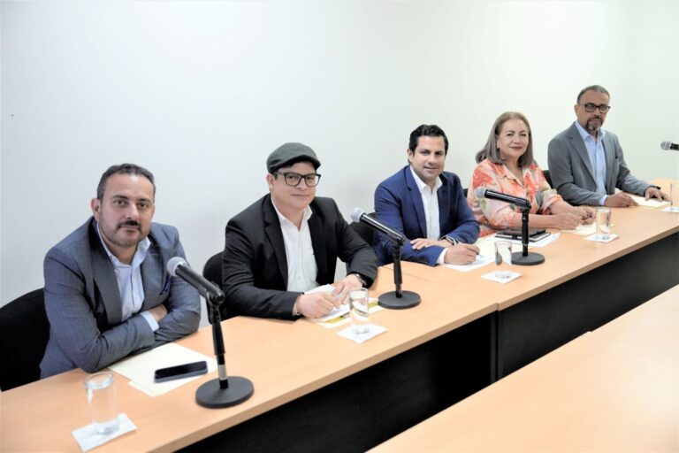 Integrantes de la comisión posan para la foto, sentado a lo largo de una mesa.