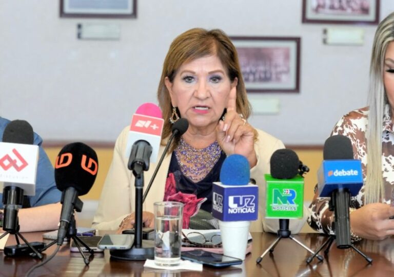 Diputada Tere Guerra aparece sentada frente a micrófonos durante conferencia de prensa.