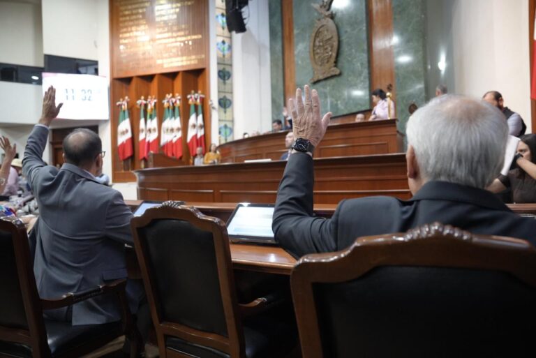 Diputados votan levantando sus manos desde sus asientos. Al fondo la Mesa Directiva.