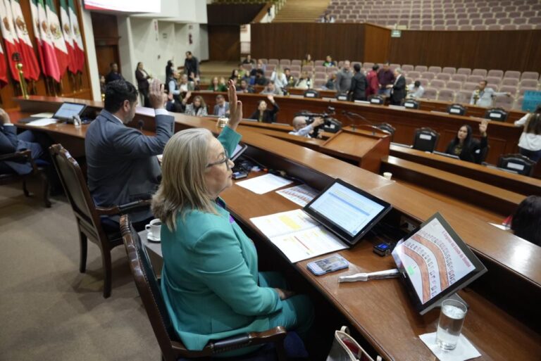 Integrantes de la Mesa Directiva votan en primer plano. Al fondo sus compañeros y compañeras hacen lo mismo.