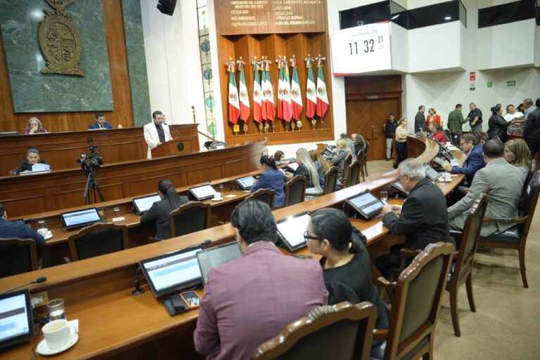 Diputado secretario da lectura en tribuna. El resto hace lo mismo desde sus asientos.