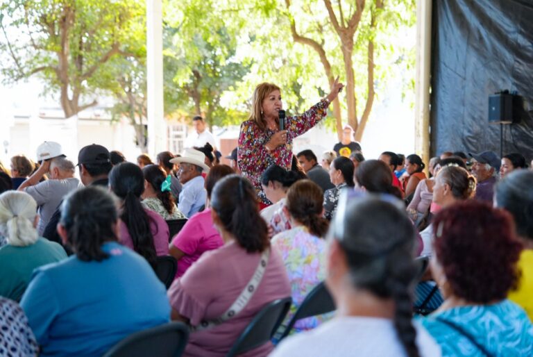 En medio de decenas de personas, Tere Guerra habla mediante micrófono y levanta en alto su puño izquierdo.