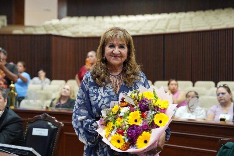 Diputada Tere Guerra sostiene ramo de flores luego de confirmar su solicitud de licencia temporal.