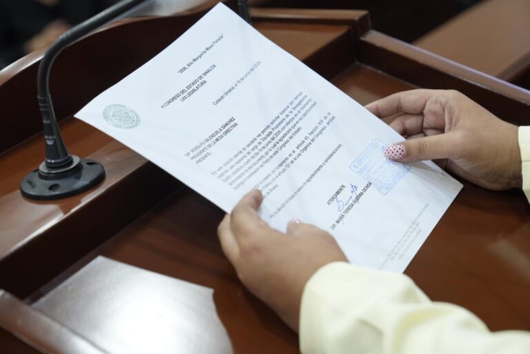 Par de manos sostiene documento al que se le da lectura en tribuna.