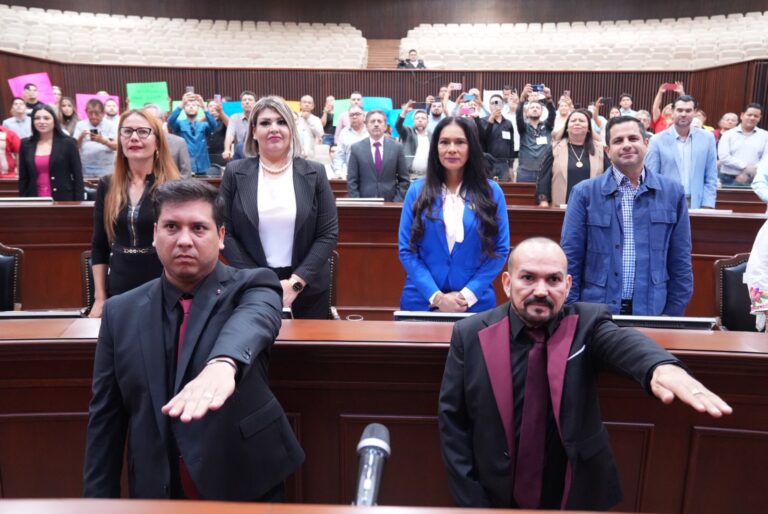 dos diputados suplentes rinden protesta levantando sus manos.