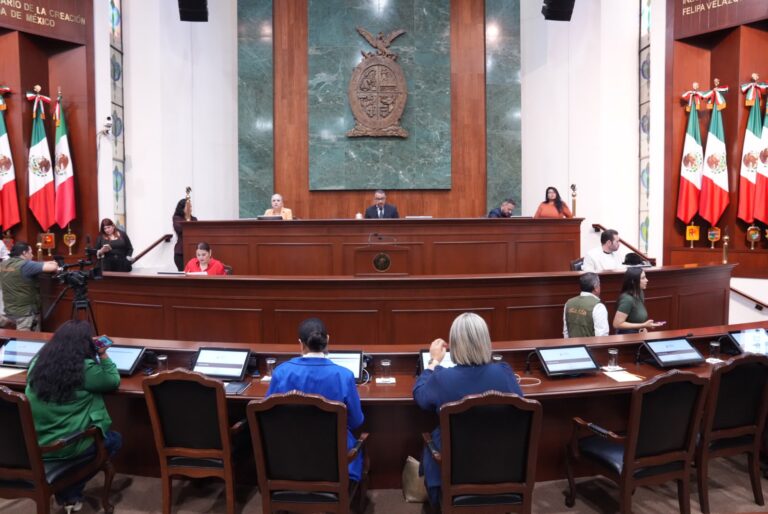 Diputadas aparecen de espaldas en sus asientos. Al fondo integrantes de la Mesa Directiva.