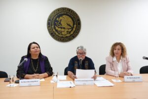 Tres integrantes de la Comisión revisan el informe de actividades.