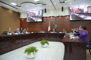 Diputados y diputados levantan sus manos durante votación.