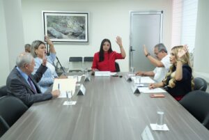 Integrantes de la Comisión votan con su mano levantada.