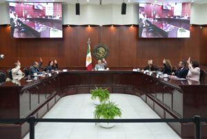 En mesa tipo herradura están sentados diputados y diputadas.