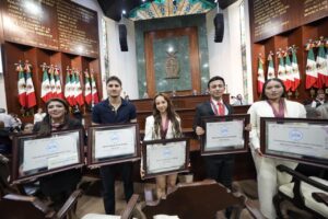 Jóvenes galardonados posan con sus premios en el Salón de Sesiones.