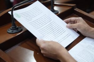 Iniciativa impresa es leída en tribuna. La sostienen dos manos.