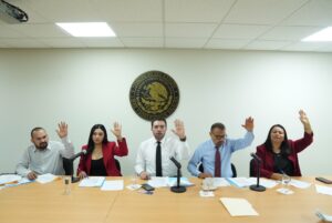Integrantes de la Comisión votan levantando sus manos.