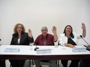 Tres diputadas votan levantando sus manos.