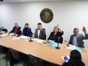 Integrantes de la comisión votan levantando sus manos.